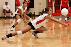 two girls playing volleyball in a gym