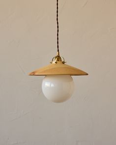 a light fixture hanging from a ceiling with a white wall behind it and a brown cord