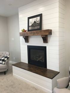 a living room with a fireplace and two chairs in front of the fireplace mantel