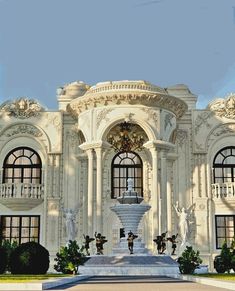 a large white building with a fountain in front of it and statues on the outside