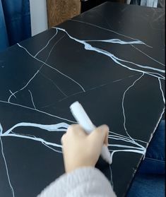 a person using a brush to paint a black table top with white lines on it