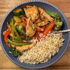 a blue bowl filled with rice, chicken and veggies