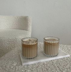 two candles sitting on top of a white table