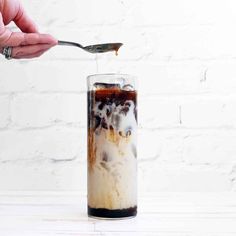 someone is spooning ice cream into a tall glass filled with chocolate and whipped cream