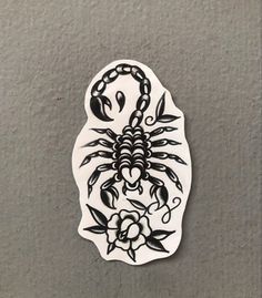 a white sticker with a scorpion on it's back and flowers in the middle