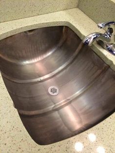 a stainless steel sink in a bathroom under a faucet