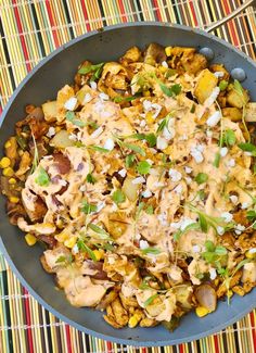 a pan filled with food sitting on top of a colorful place mat next to a spoon