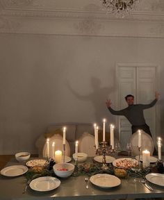 a man standing in front of a table full of food and candles with his arms wide open