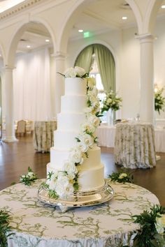 a wedding cake sitting on top of a table covered in white flowers and greenery