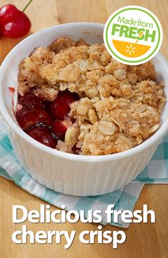 a close up of a bowl of food on a table with cherries in the background