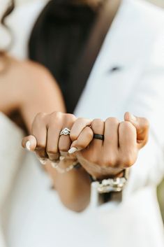 a bride and groom holding hands with their wedding rings on each hand, while the other is wearing a white tuxedo