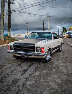 an old car is parked on the side of the road with power lines in the background