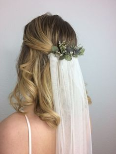 the back of a bride's head wearing a veil with flowers and leaves on it