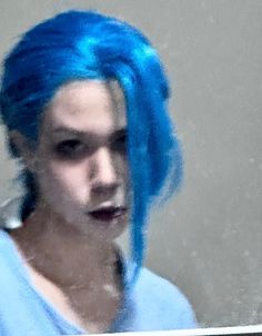 a woman with blue hair is reflected in a mirror