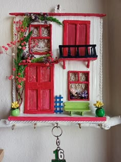 a red and white doll house is hanging on the wall next to a keychain