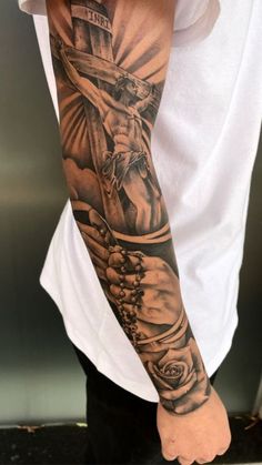 a man's arm with a cross and roses tattoo on the left side of his arm