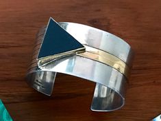 "Stunning cuff bracelet designed by M & J Savitt. Sterling & 14 karat gold with a triangle shaped black onyx set in a 14 karat bezel & gold inlaid stripe. Signed and stamped. Measures approximately 1 1/8\" wide." Modern Black Enamel Jewelry, Contemporary Adjustable Formal Jewelry, Modernist Jewelry Bangle With Polished Finish, Modernist Polished Cuff Bracelet For Formal Occasions, Modern Black Bangle Jewelry, Contemporary Adjustable Jewelry With Polished Finish, Contemporary Adjustable Polished Jewelry, Unique Polished Cuff Jewelry, Modernist Sterling Silver Adjustable Bracelet For Formal Occasions