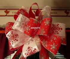 a red and white christmas bow with snowflakes on the top is hanging in front of a window