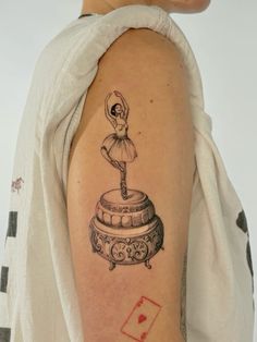 a woman's arm with a tattoo on it that has a ballerina standing on top of a barrel