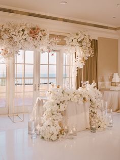 a table with flowers and candles in front of a window at a wedding reception on the beach