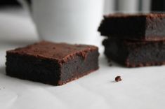 three pieces of brownie sitting on top of a table next to a white cup