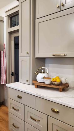 a kitchen with white cabinets and wooden trays on the counter top next to an oven