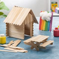 a wooden toy house sitting on top of a table next to other toys and supplies