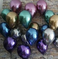 many metallic balloons are arranged in a circle on a brick wall, with one purple and the other green