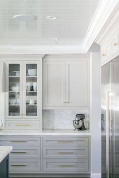 a kitchen with white cabinets and marble counter tops