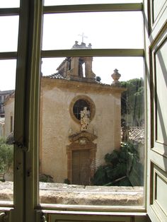 an old building seen through a window with a statue on the front and side of it