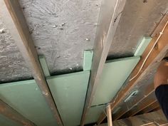 a man is working on the ceiling in an unfinished room with metal beams and green paint