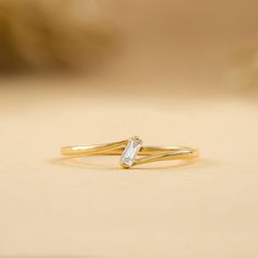 a yellow gold ring with a white diamond on the top, and a thin band around it