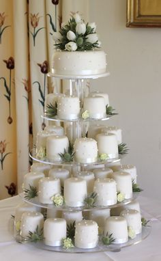 a tiered cake with white frosting and flowers on the top is surrounded by candles