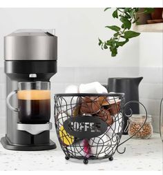 a coffee maker sitting on top of a counter next to a basket filled with pastries