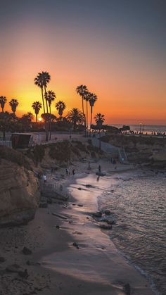 the sun is setting at the beach with palm trees