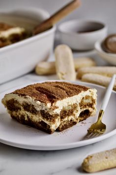 a piece of cake sitting on top of a white plate next to bananas and cinnamon sticks