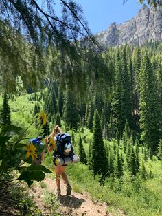 a woman hikes up a trail in the mountains with backpacks on her back