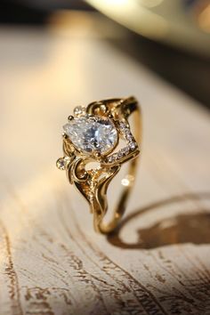 a gold ring with a white diamond in the center on top of a wooden table