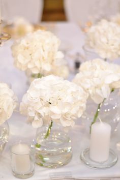 white flowers in vases and candles on a table