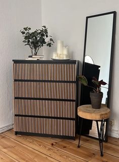 a black and white dresser sitting next to a mirror on top of a wooden floor