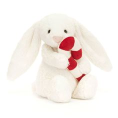 a white stuffed rabbit with a red and white striped scarf around its neck, sitting against a white background