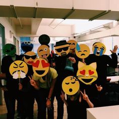 a group of people standing next to each other holding up paper cutouts with faces on them