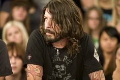 a man with long hair sitting in front of a crowd