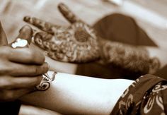 two people holding their hands together with henna on the other hand and one woman's arm