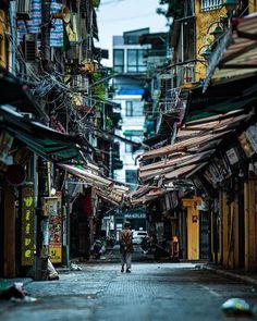 a person walking down an alley way with lots of buildings in the backgroud