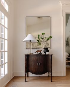 a room with a mirror, table and lamp on the wall next to an open door