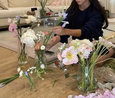 a woman arranging flowers in vases on the floor