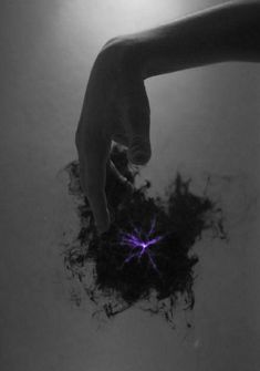 a person's hand reaching for something in the air with purple light coming from it