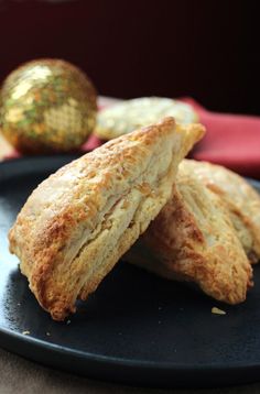 two biscuits on a black plate next to a gold ornament in the background