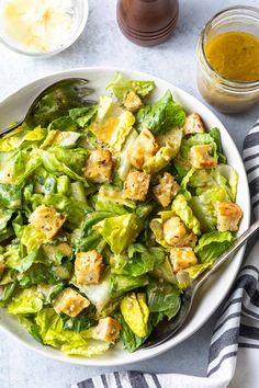 a white bowl filled with lettuce salad next to a jar of mustard sauce